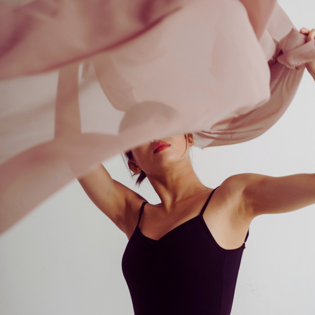 A woman moving freely beneath flowing pink silk
