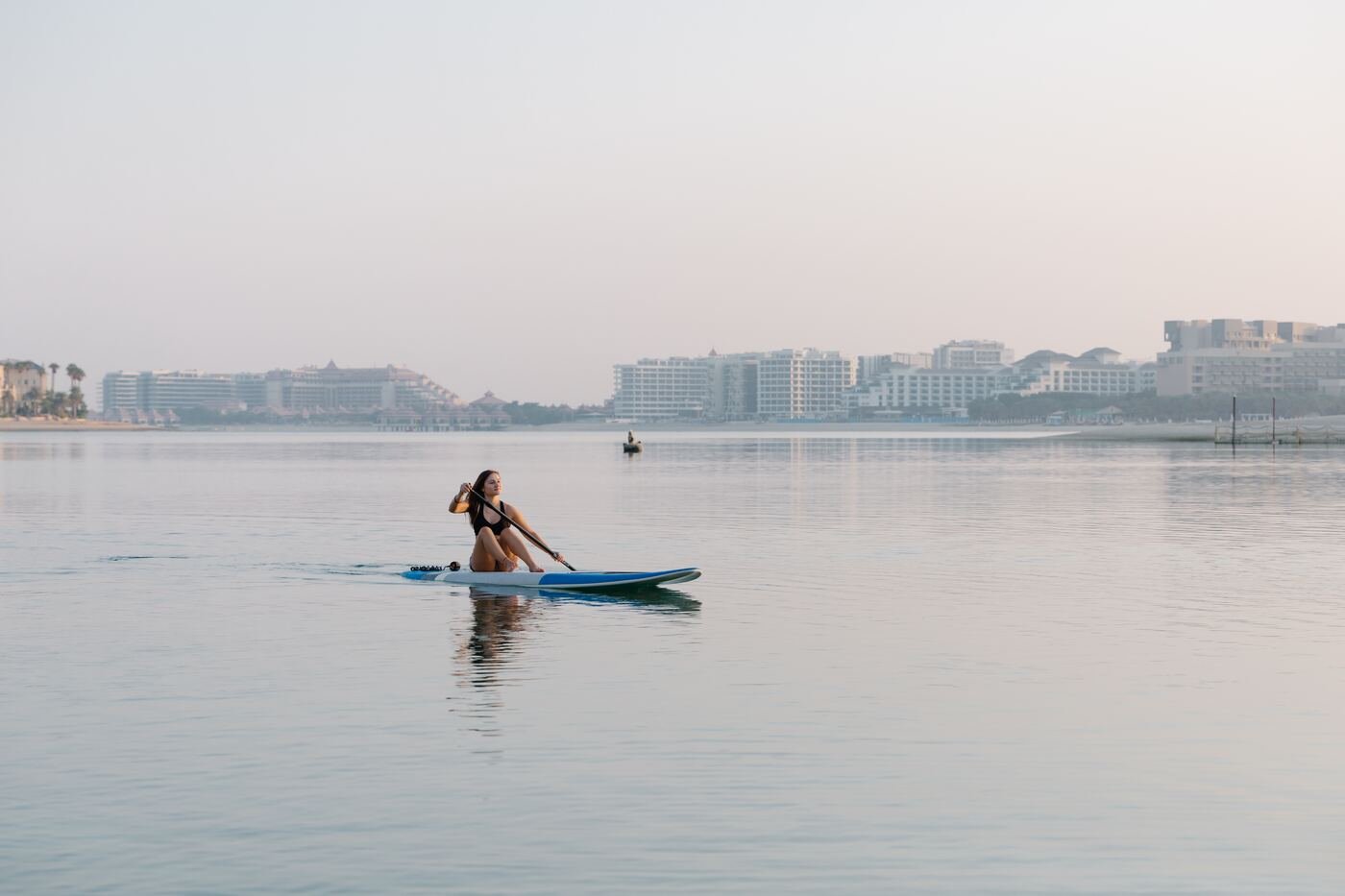 A woman paddleboarding on calm water in the UAE at sunrise